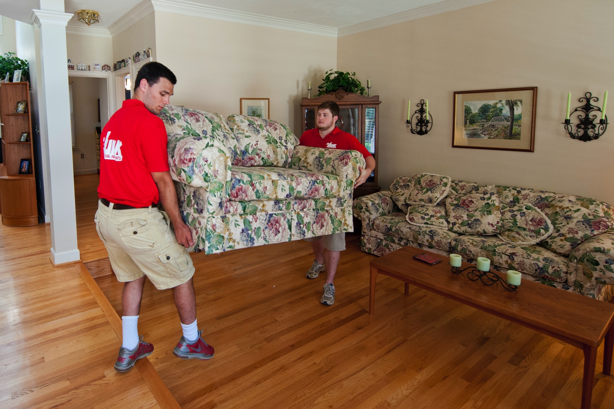 two men moving a love seat inside a house