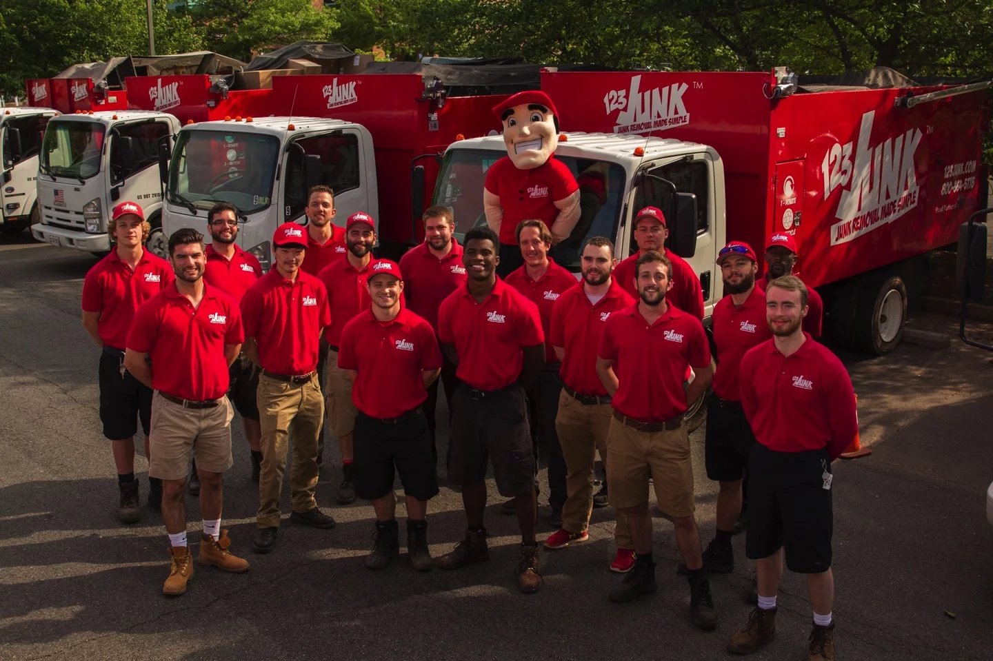 several men posing in front of company moving trucks