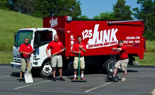 Four workers in red shirts standing in front of a 123JUNK truck with cleaning tools