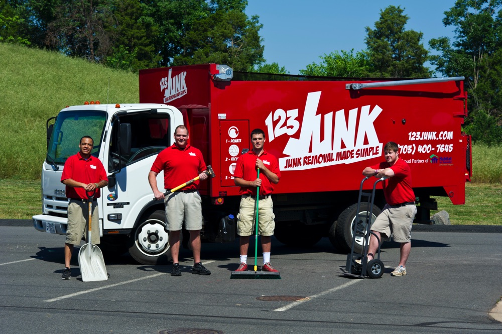 four men posing in front of company moving truck