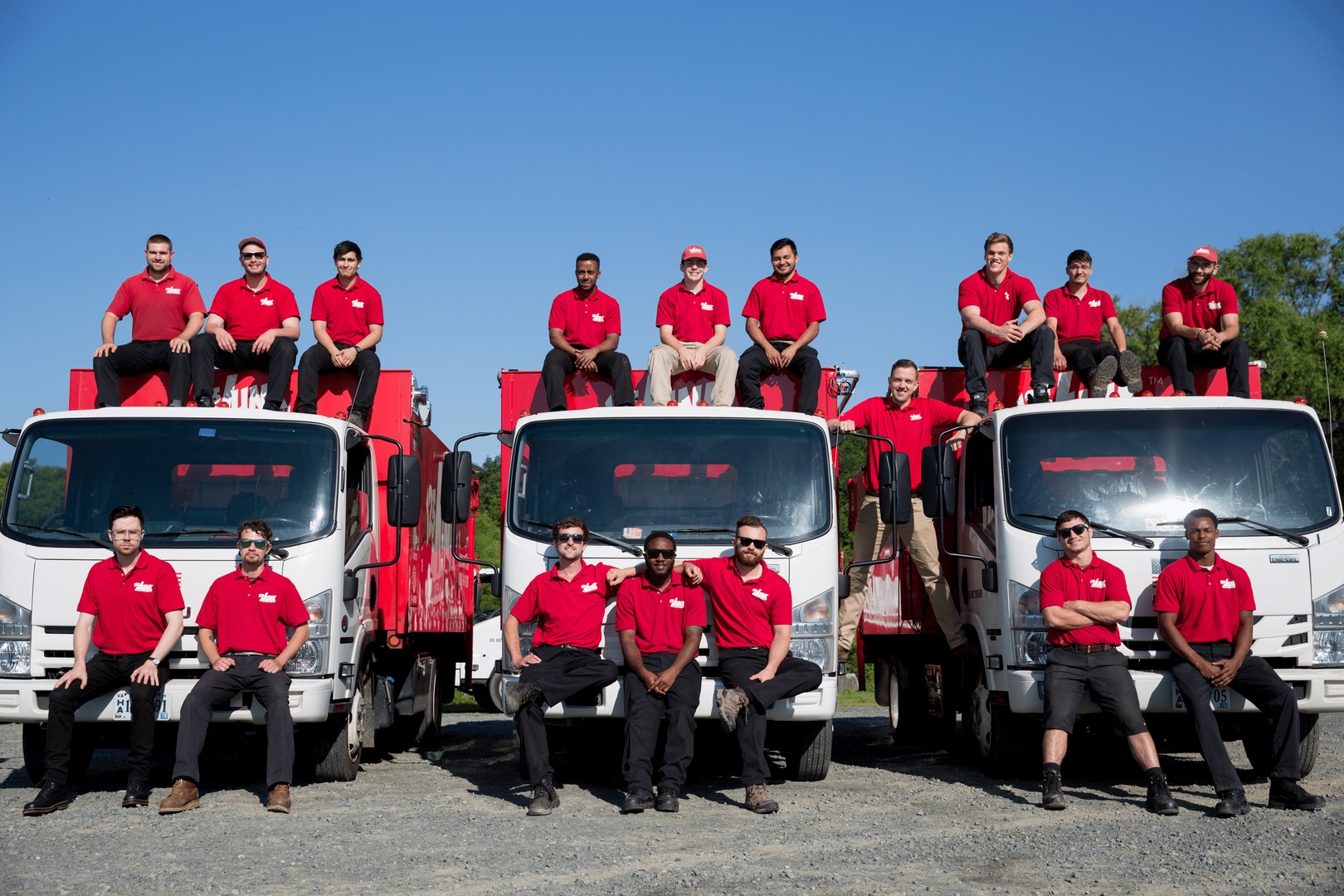 several people posing around three company trucks
