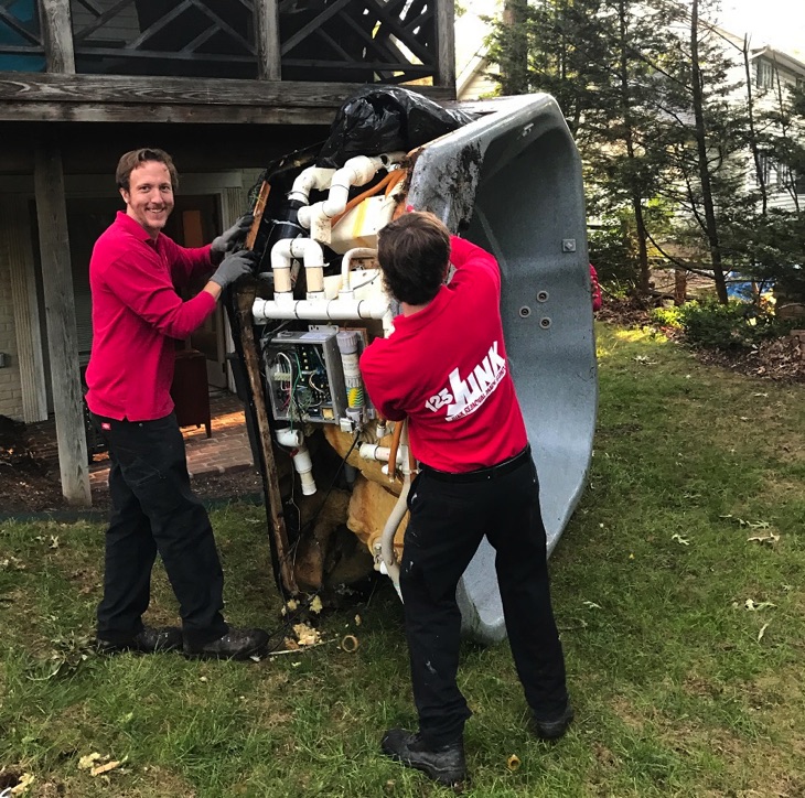 two men moving a hot tub outside