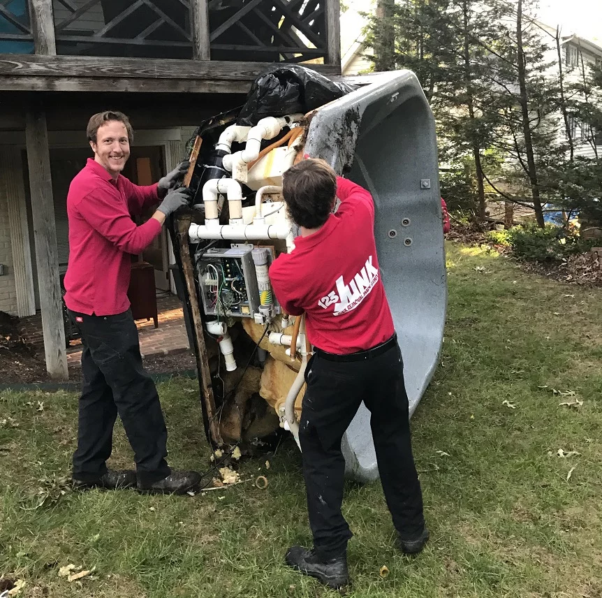 two men moving a hot tub outside