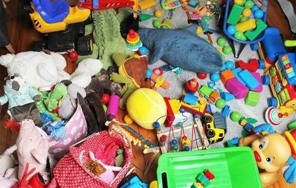 Pile of assorted children’s toys, including stuffed animals, blocks, and vehicles, scattered on the floor