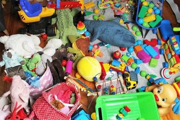 Pile of assorted children’s toys, including stuffed animals, blocks, and vehicles, scattered on the floor