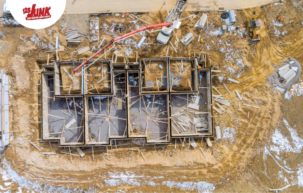 Aerial view of a construction site with the foundation of a building surrounded by scattered debris and equipment