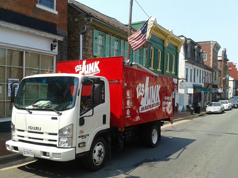 123junk truck driving through the business district for commercial junk removal services