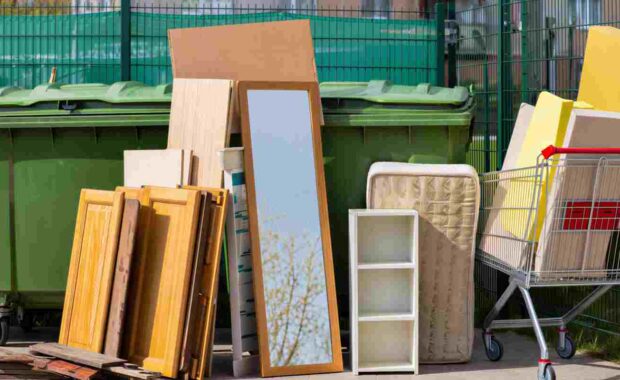 Bulky Household Items Stacked Near Outdoor Trash Bin
