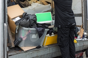 Junk Removal Worker Loading Mixed Waste and Household Items to Truck after Estate Cleanout