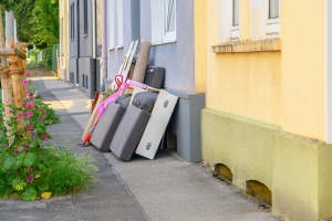 Pile of Leftover Furniture and Debris on Sidewalk of Apartment Buildings