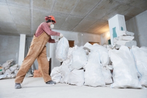 Worker Collecting Junk in Bags During Property Cleanout