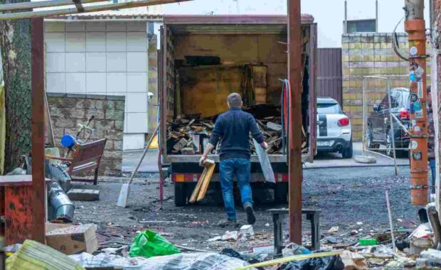 Junk Removal Worker Loading Construction Waste to Dumpster