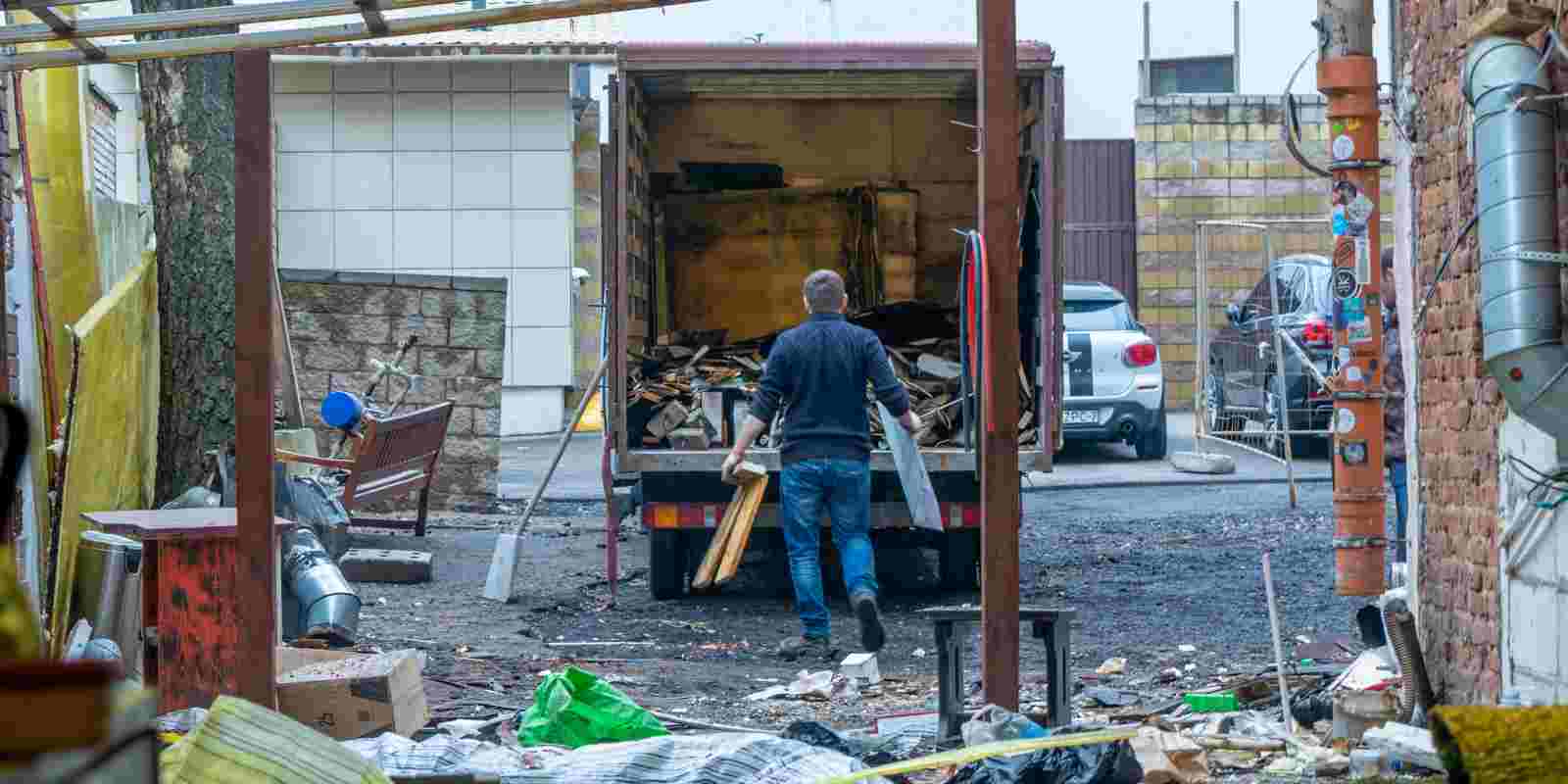 Junk Removal Worker Loading Construction Waste to Dumpster