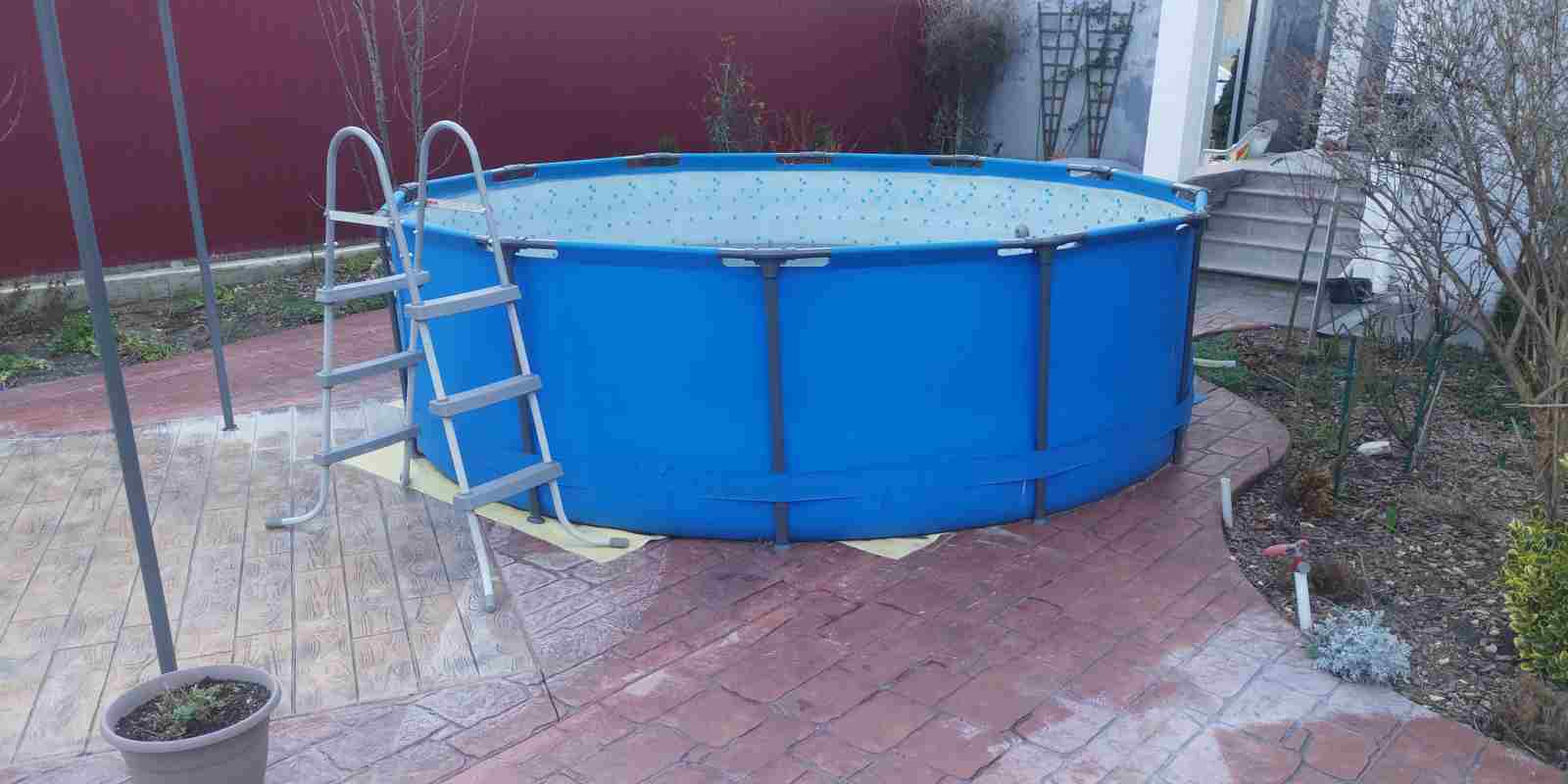 Above-Ground Swimming Pool is Set on a Paved Area Near the House
