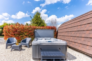An Empty Hot Tub on Gravel Ground Next to a Wooden Fence for Removal