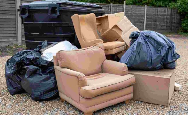 Discarded Old Furniture, Broken Armchairs, Cardboard Boxes, and Garbage Bags in Yard for Removal